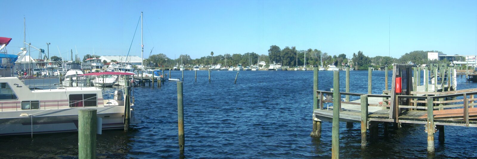 Panorama of the Anclote River at the Tarpon Springs sponge docks, with boats, wooden pilings and docks under a blue sky